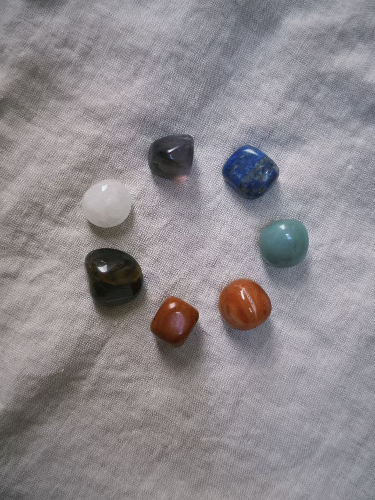 Seven healing stones arranged in a circle on soft linen